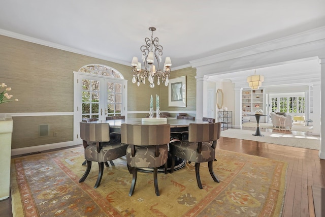dining area with crown molding, an inviting chandelier, french doors, hardwood / wood-style floors, and wallpapered walls