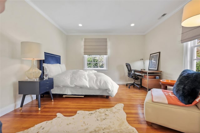 bedroom with crown molding, multiple windows, and wood finished floors