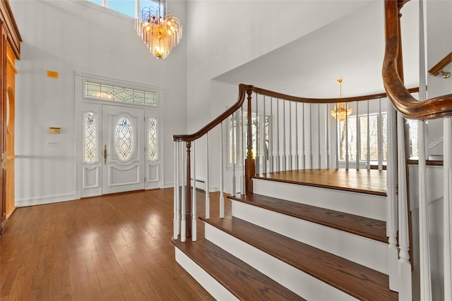 foyer featuring a high ceiling, stairway, hardwood / wood-style floors, and a notable chandelier