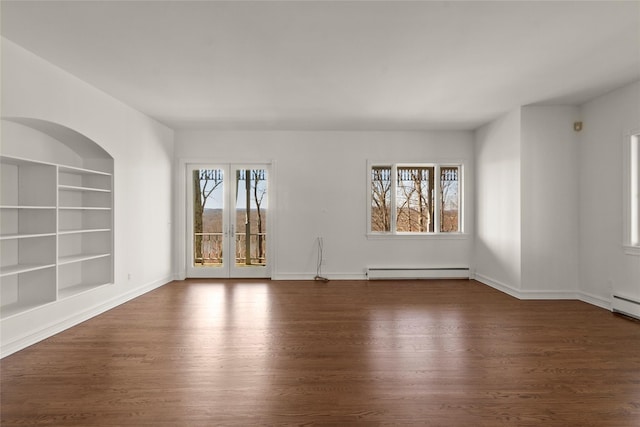 unfurnished room with baseboards, wood finished floors, built in features, and a baseboard radiator