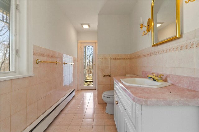 bathroom featuring toilet, tile walls, baseboard heating, vanity, and tile patterned floors