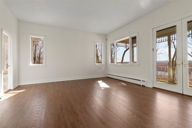 spare room with baseboard heating, baseboards, and wood finished floors