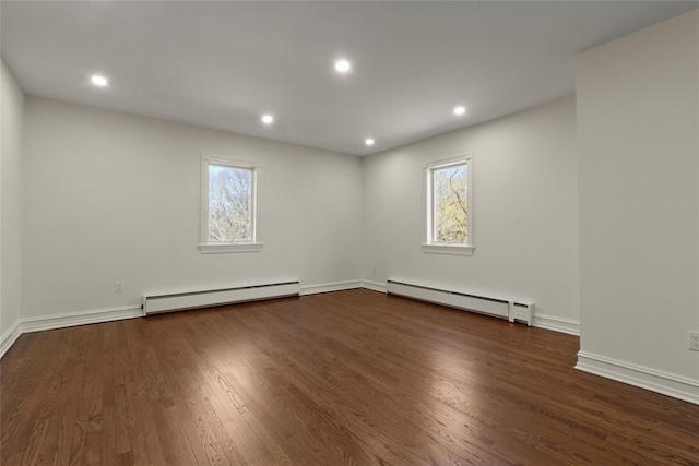 spare room with recessed lighting, a baseboard heating unit, and wood finished floors