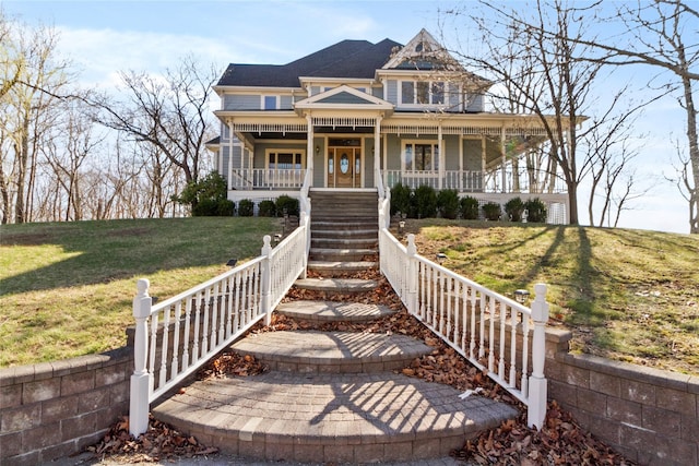 victorian house featuring a porch, a front yard, and stairway