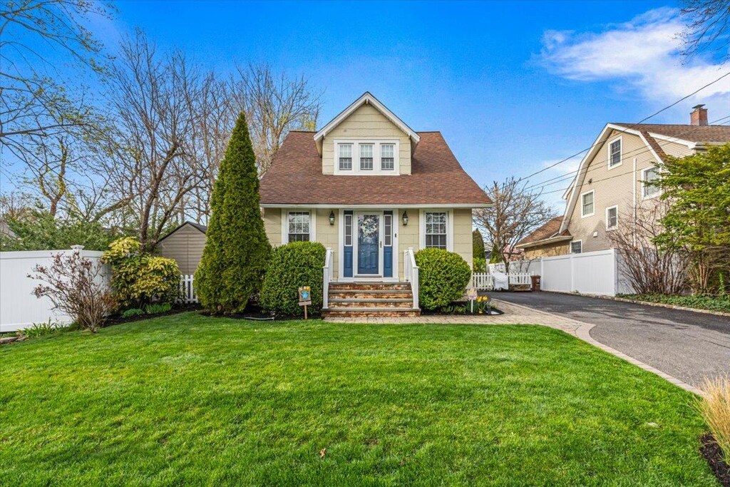 view of front of property with aphalt driveway, a front yard, and fence