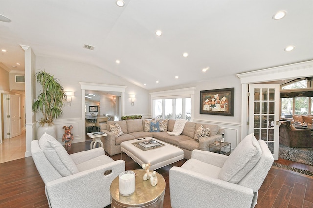 living area featuring lofted ceiling, a wainscoted wall, wood finished floors, visible vents, and a decorative wall