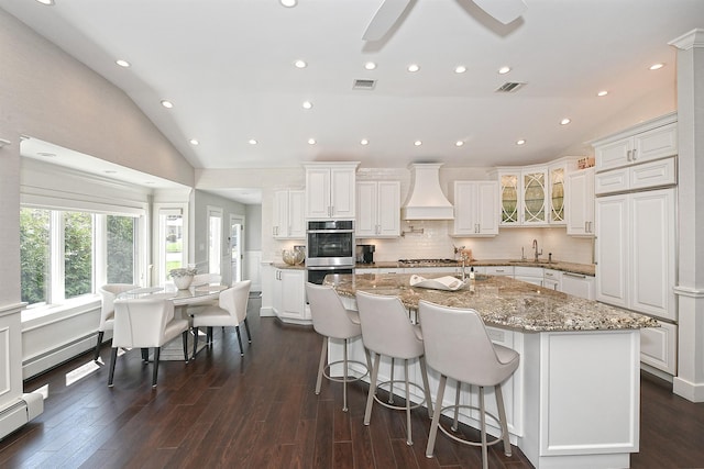 kitchen with a baseboard radiator, vaulted ceiling, custom exhaust hood, a sink, and a baseboard heating unit