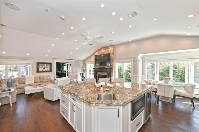 kitchen with lofted ceiling, visible vents, stainless steel microwave, open floor plan, and white cabinetry