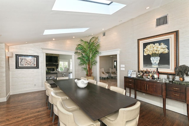 dining room with baseboards, visible vents, lofted ceiling with skylight, and dark wood-style floors