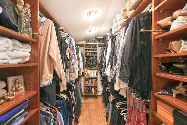 walk in closet featuring lofted ceiling, wood finished floors, and a baseboard radiator