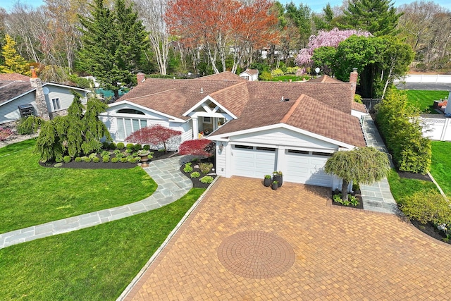 view of front of property featuring an attached garage, a shingled roof, a front yard, and decorative driveway