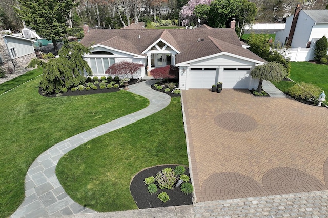 ranch-style house featuring a chimney, fence, decorative driveway, and a front yard