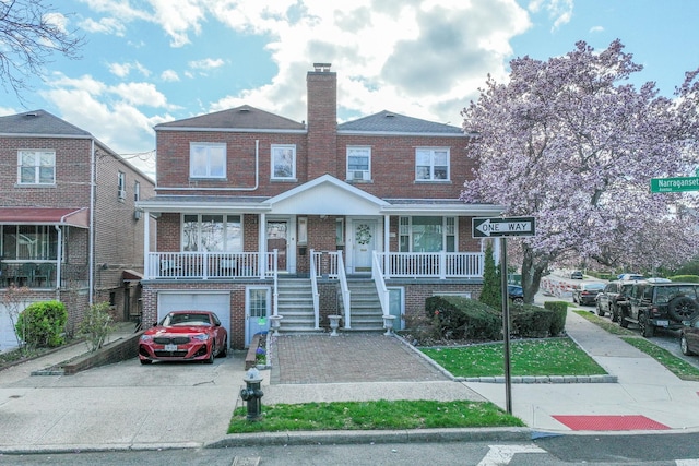view of front of home with covered porch, a garage, stairway, brick siding, and driveway
