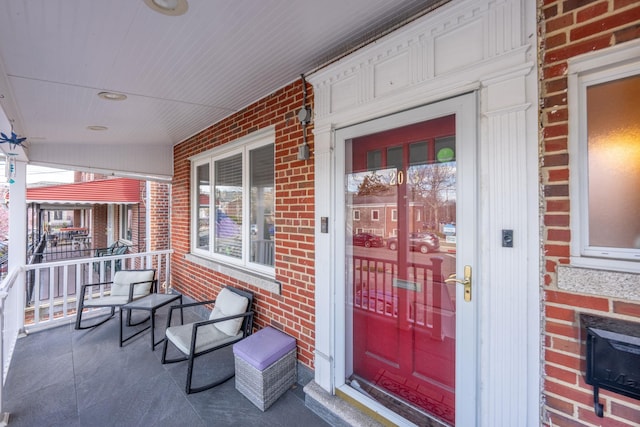 doorway to property featuring brick siding and covered porch