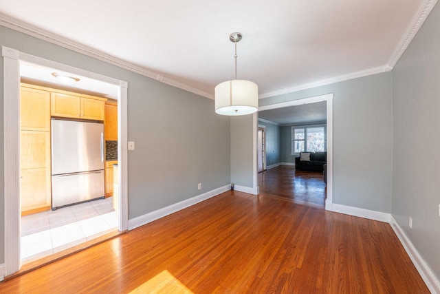 unfurnished room with crown molding, light wood-style flooring, and baseboards