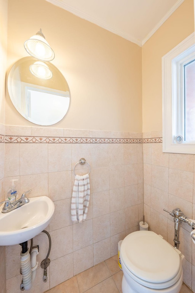 half bath with a sink, ornamental molding, toilet, tile walls, and tile patterned floors