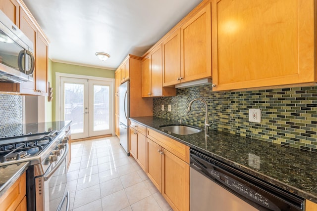 kitchen featuring french doors, tasteful backsplash, appliances with stainless steel finishes, and a sink