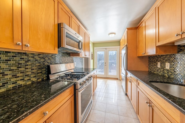 kitchen featuring stainless steel appliances, french doors, light tile patterned flooring, and decorative backsplash