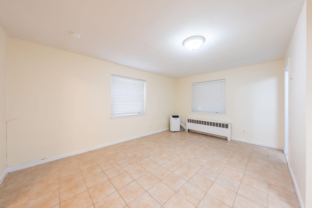 unfurnished room with radiator heating unit, light tile patterned flooring, and baseboards