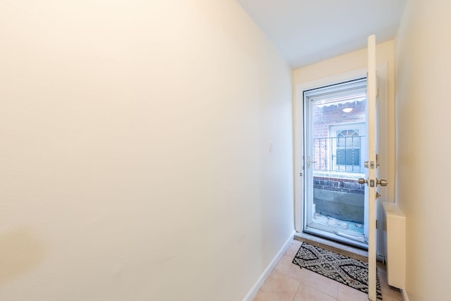 entryway with light tile patterned floors, baseboards, and lofted ceiling