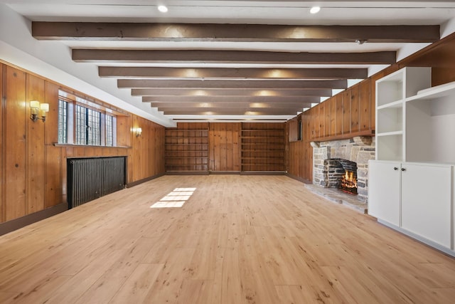 86 Hereford Rd, Bronxville, NY 10708 - unfurnished living room featuring a stone fireplace, beamed ceiling, light wood-style flooring, and wood walls