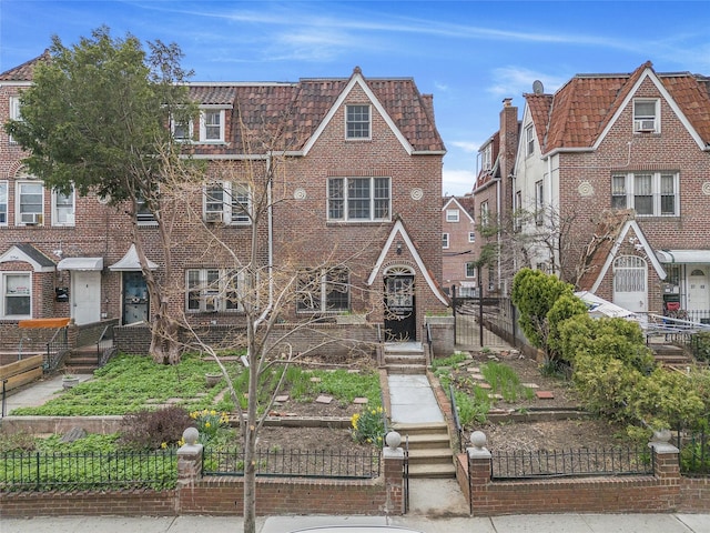 view of front of property featuring mansard roof, a fenced front yard, and brick siding