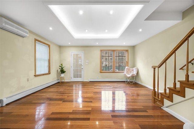 entrance foyer featuring a tray ceiling, wood-type flooring, a wall unit AC, and baseboard heating