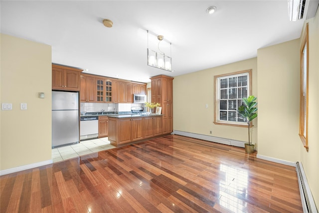 kitchen with light wood-style floors, glass insert cabinets, a baseboard radiator, and appliances with stainless steel finishes