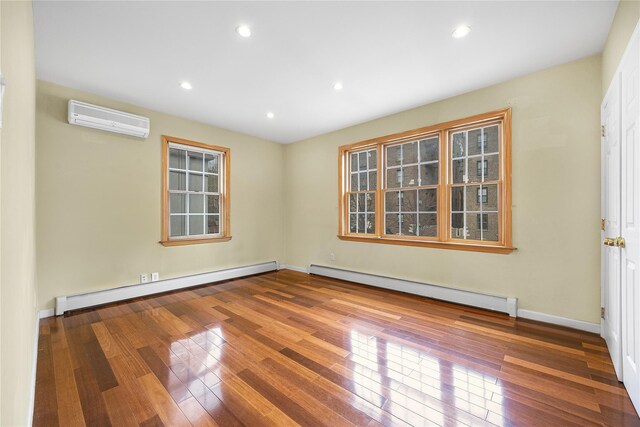 empty room with baseboard heating, a wall mounted AC, and hardwood / wood-style flooring