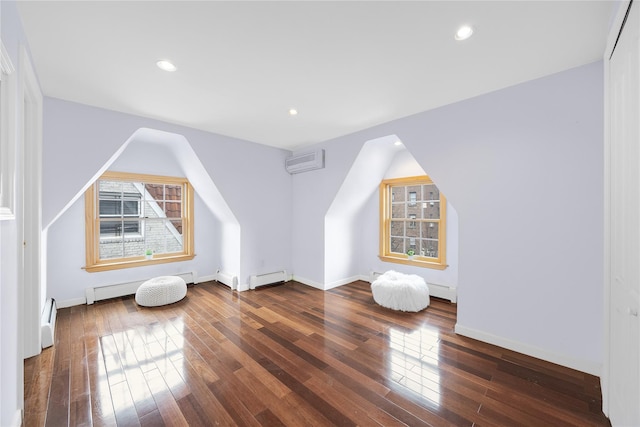 bonus room with a baseboard heating unit, hardwood / wood-style flooring, and an AC wall unit
