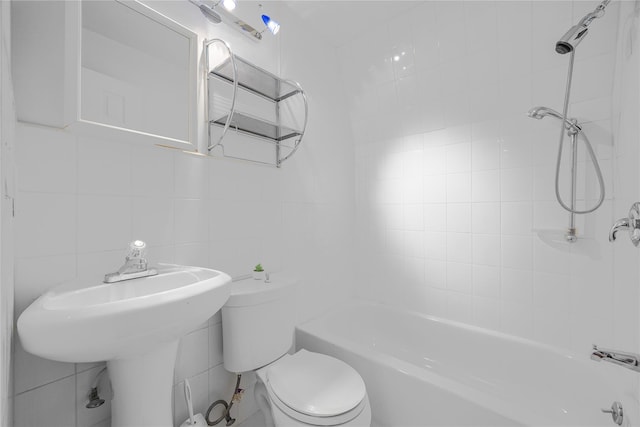 bathroom with toilet, a sink, washtub / shower combination, tile walls, and backsplash