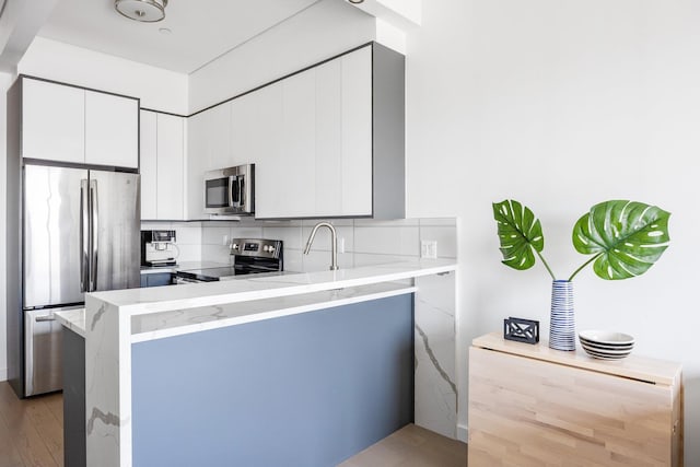 1043 Halsey St Unit 4, Brooklyn, NY 11207 - kitchen with a peninsula, appliances with stainless steel finishes, backsplash, and white cabinets