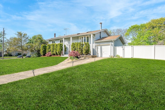 view of front of home with concrete driveway, an attached garage, fence, and a front yard