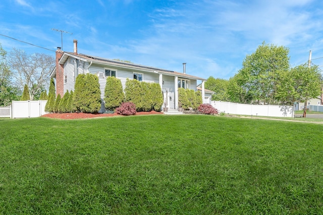 view of front of house with fence, a chimney, and a front yard