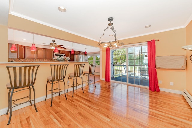 dining room with baseboards, ornamental molding, ceiling fan with notable chandelier, and light wood-type flooring