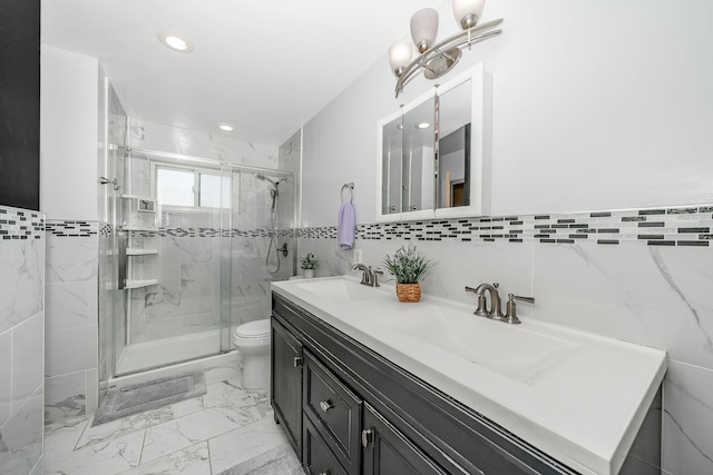 full bath featuring double vanity, toilet, tile walls, a sink, and a marble finish shower