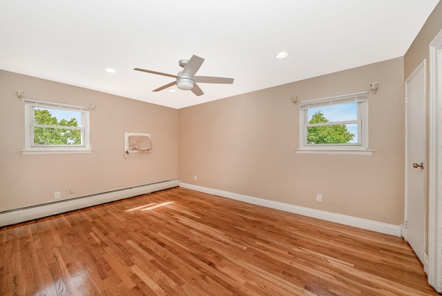 empty room featuring a healthy amount of sunlight, a baseboard radiator, and light wood-type flooring
