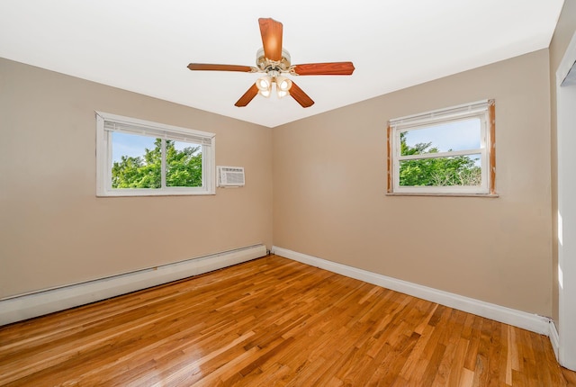 spare room with baseboard heating, a ceiling fan, baseboards, a wall unit AC, and light wood-type flooring