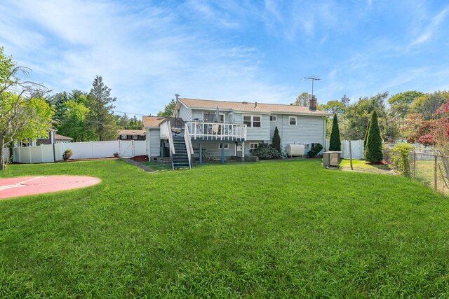 back of property with a deck, a fenced backyard, a chimney, a lawn, and stairway