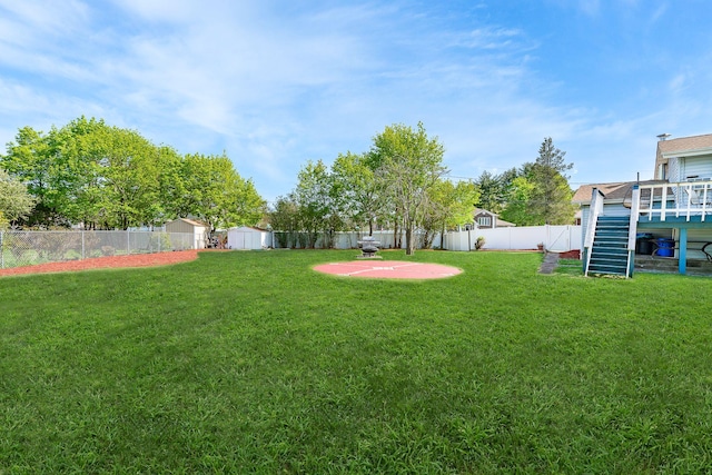 view of yard with a wooden deck, an outdoor structure, a shed, a fenced backyard, and stairs