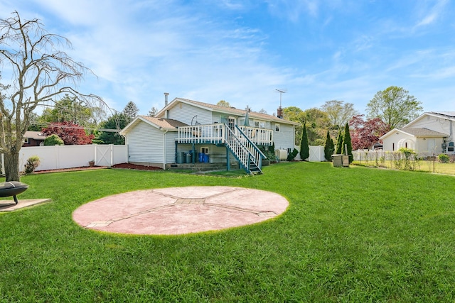 rear view of property with a fenced backyard, a wooden deck, a yard, and stairway