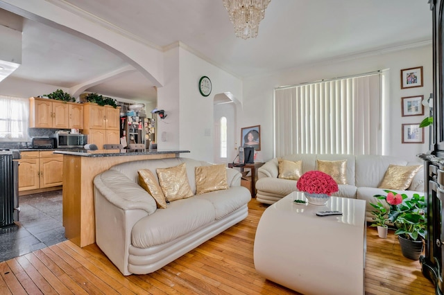 living area featuring a toaster, arched walkways, and light wood finished floors
