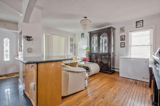 living area with baseboard heating, ornamental molding, and light wood-style floors
