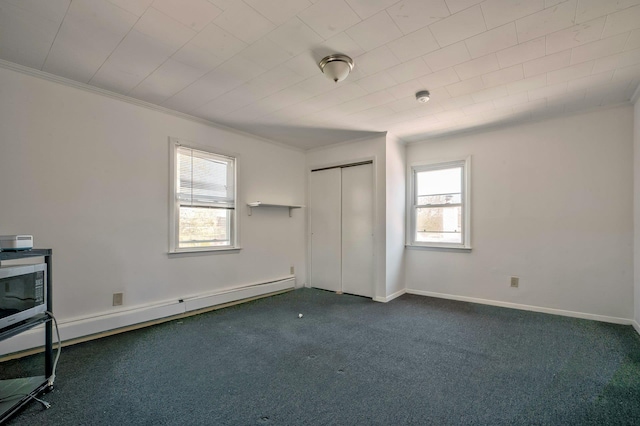 unfurnished bedroom featuring crown molding, dark colored carpet, a baseboard heating unit, baseboards, and a closet