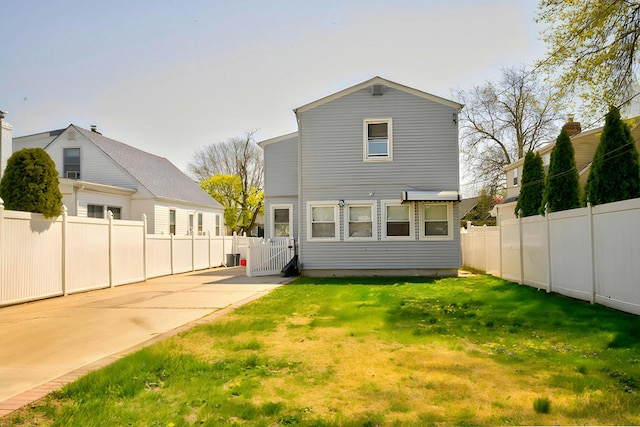 back of property with fence, a gate, and a lawn