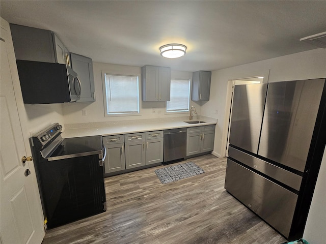 648 Lybolt Rd, Middletown, NY 10941 - kitchen featuring stainless steel appliances, a sink, wood finished floors, gray cabinets, and light countertops