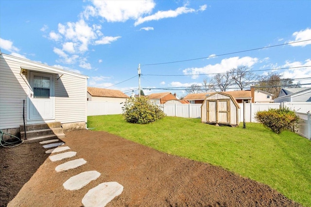 view of yard featuring a storage shed, a fenced backyard, an outbuilding, and entry steps