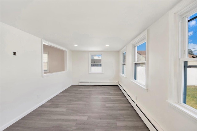 unfurnished room with a baseboard radiator, baseboards, a healthy amount of sunlight, and wood finished floors