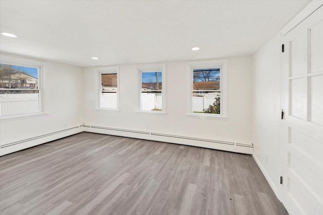 interior space featuring a baseboard heating unit, baseboards, light wood-style floors, and recessed lighting