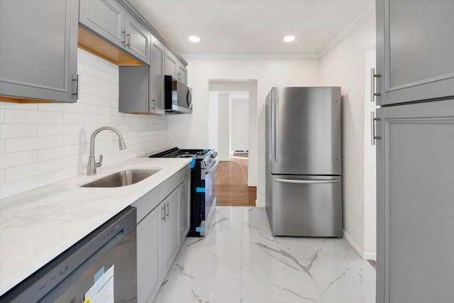 kitchen featuring crown molding, a sink, decorative backsplash, gray cabinets, and stainless steel appliances